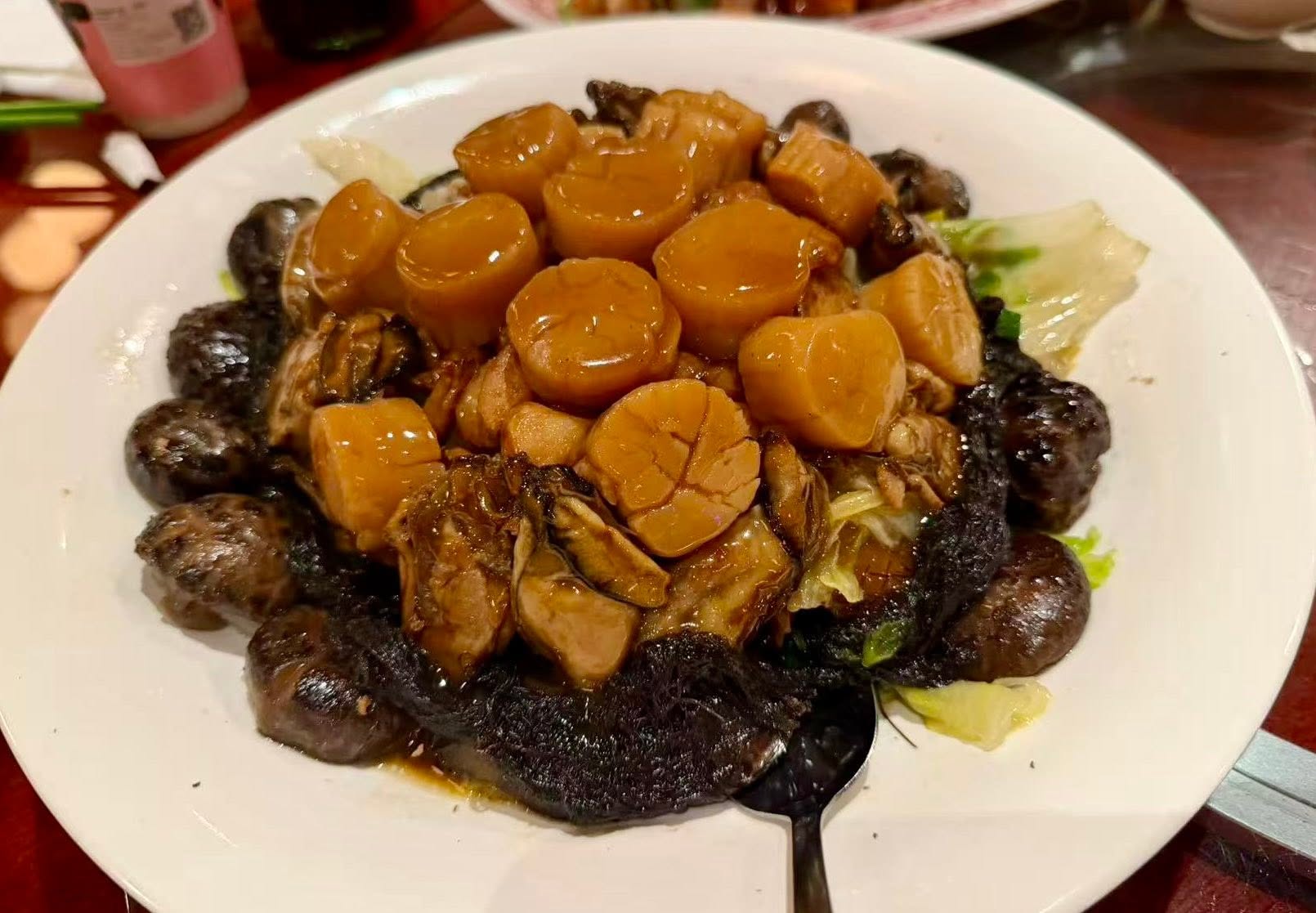 A dish of scallops and mushrooms on a white plate