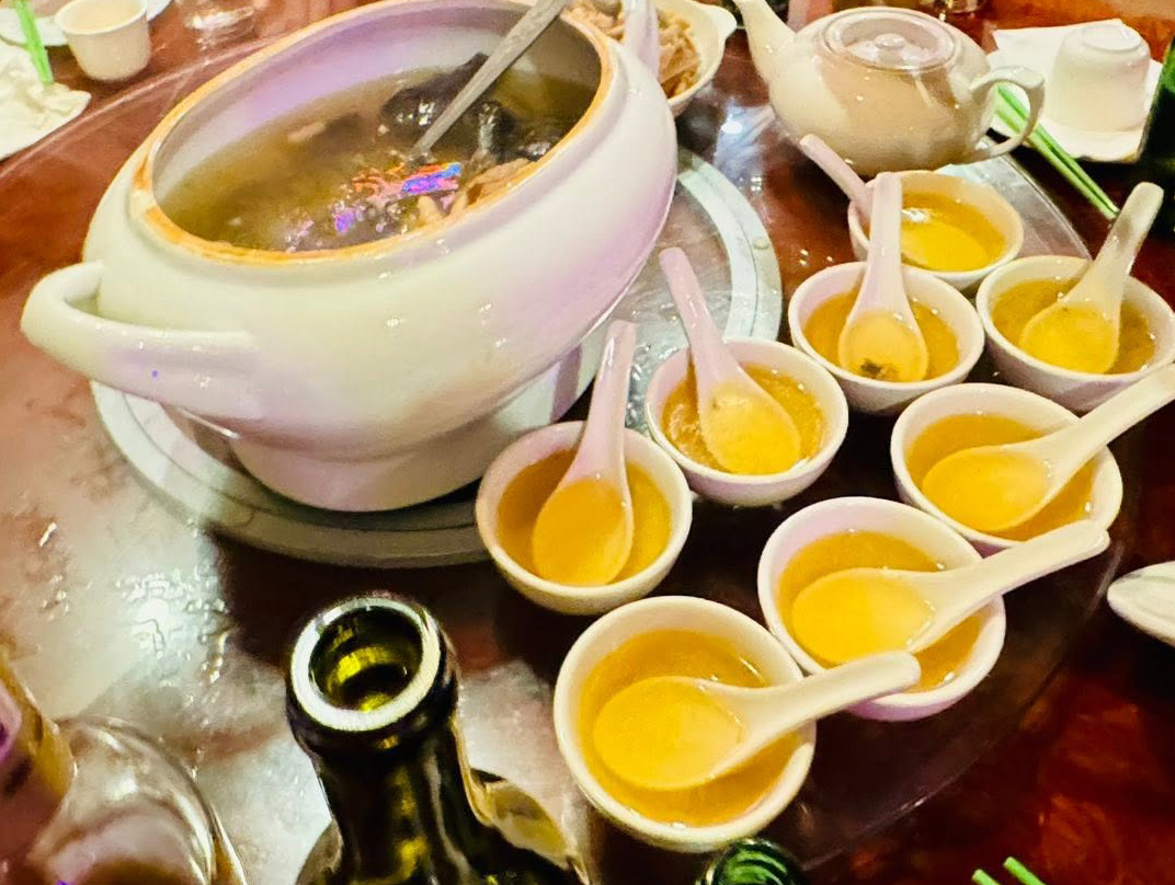 A covered soup bowl with small cups arranged alongside
